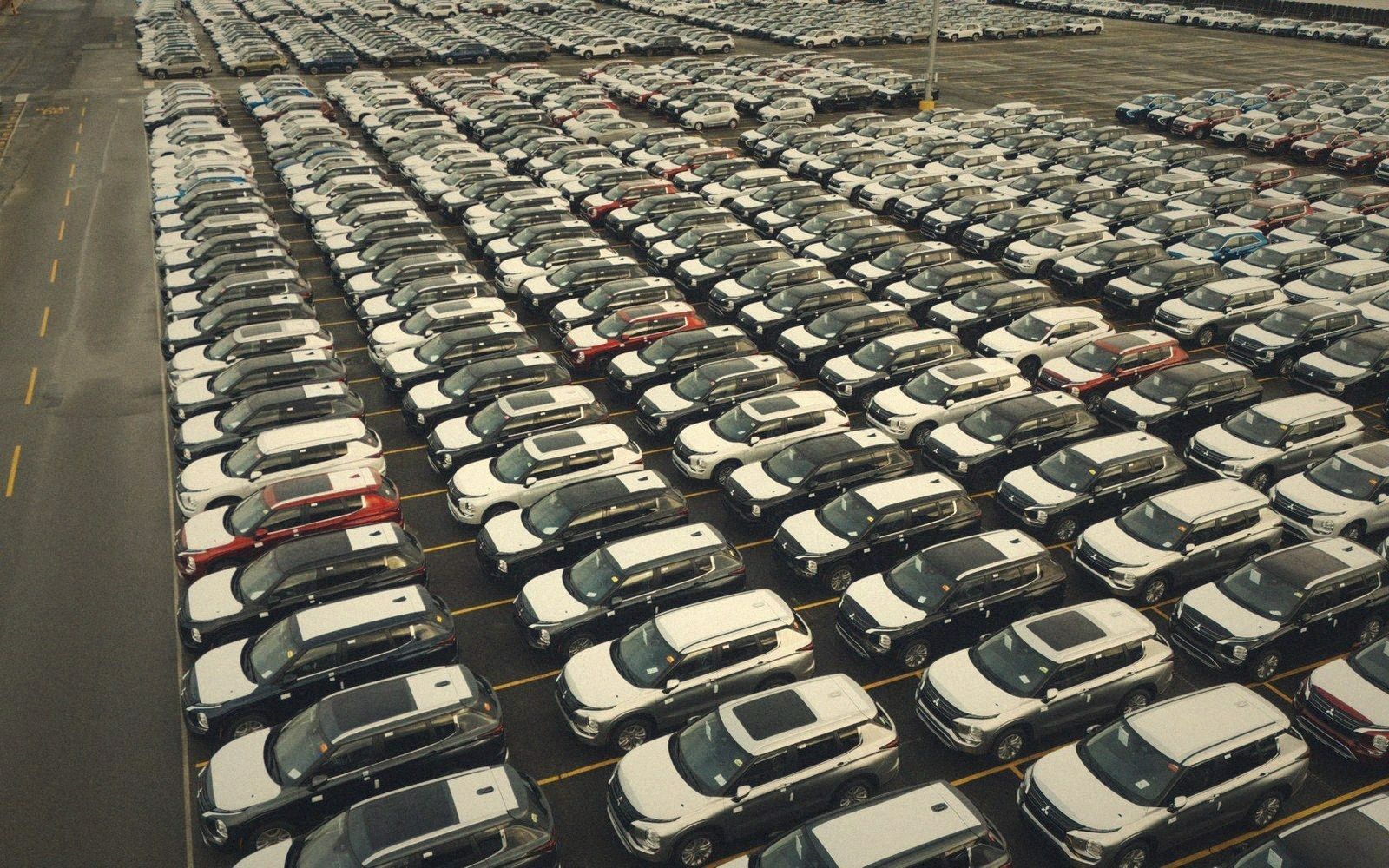 Rows of new cars parked in neat lines at a large storage lot, seen from above